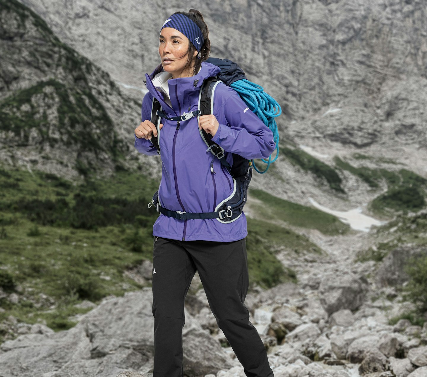 Schöffel Venturi, Frau beim Wandern in lila Outdoorjacke mit Kletterausrüstung vor felsiger Bergkulisse, Schöffel