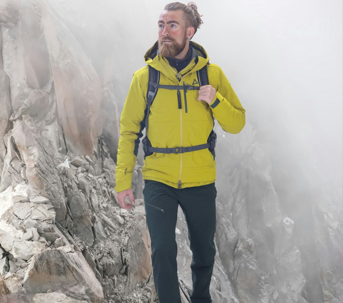 Schöffel Venturi, Mann mit gelber Funktionsjacke und Rucksack auf nebligem Hochgebirgspfad, Schöffel
