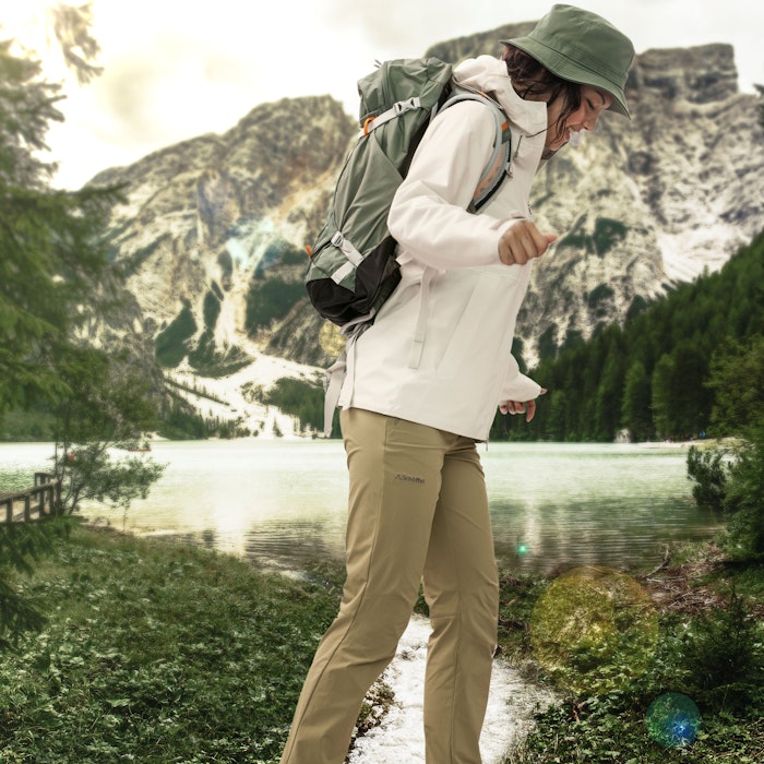 Softshelljacke waschen, Frau in Schöffel-Outfit balanciert auf einem Baumstamm vor einer See- und Berglandschaft, Schöffel