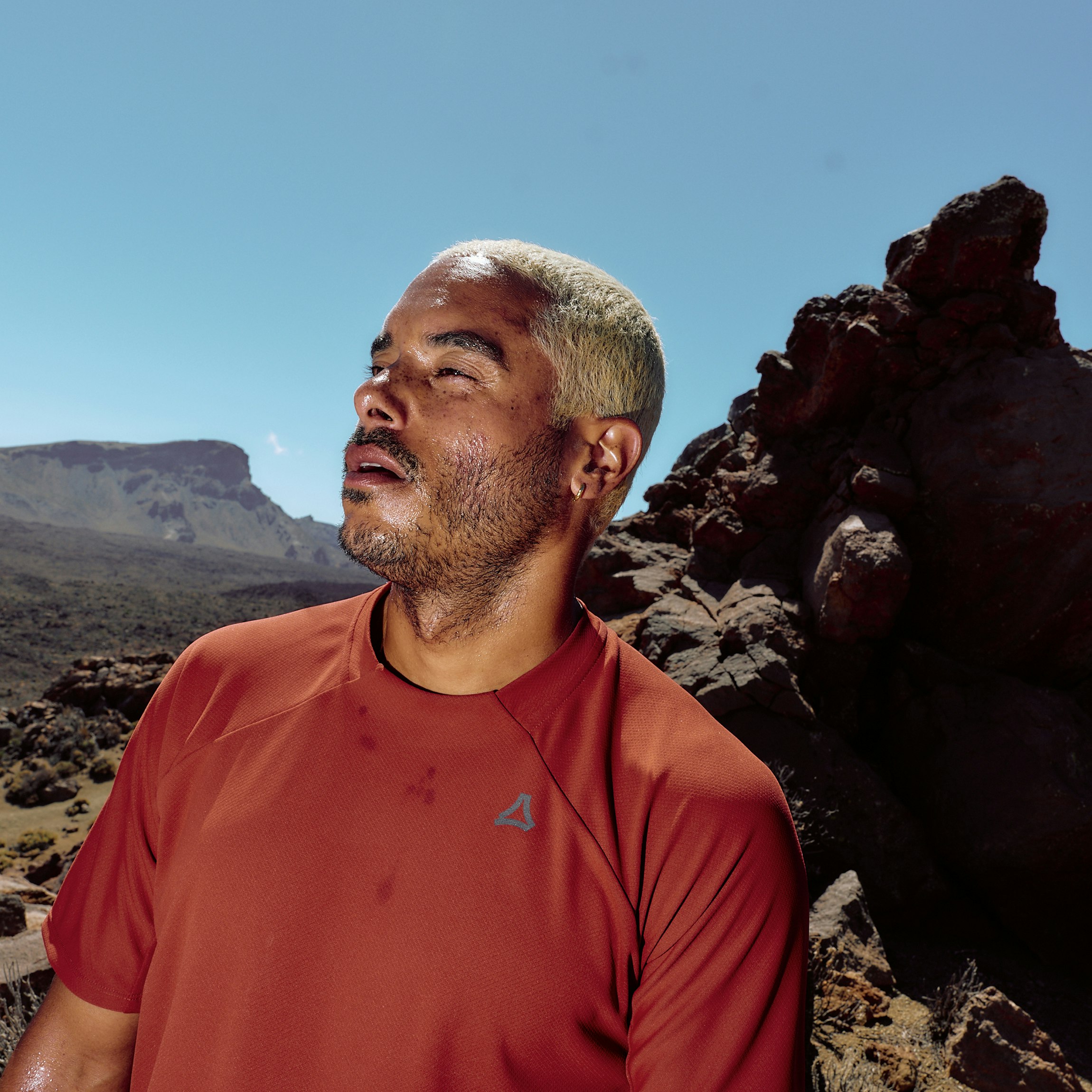 The sun shines on the face of a man dressed in a red shirt.