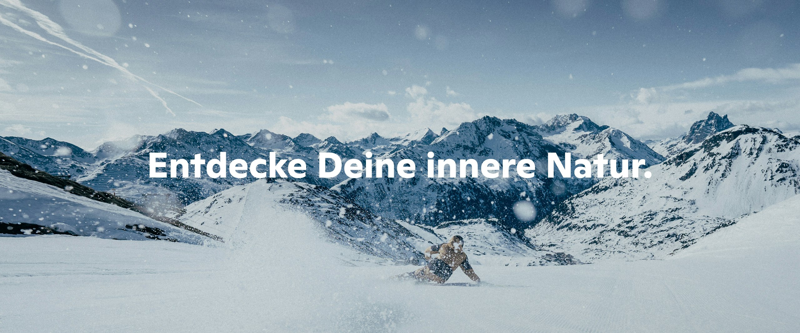 Eine Person fährt mit Skiern über die Piste, Bergpanorama im Hintergrund und die Aufschrift "Entdecke deine innere Natur", Schöffel.