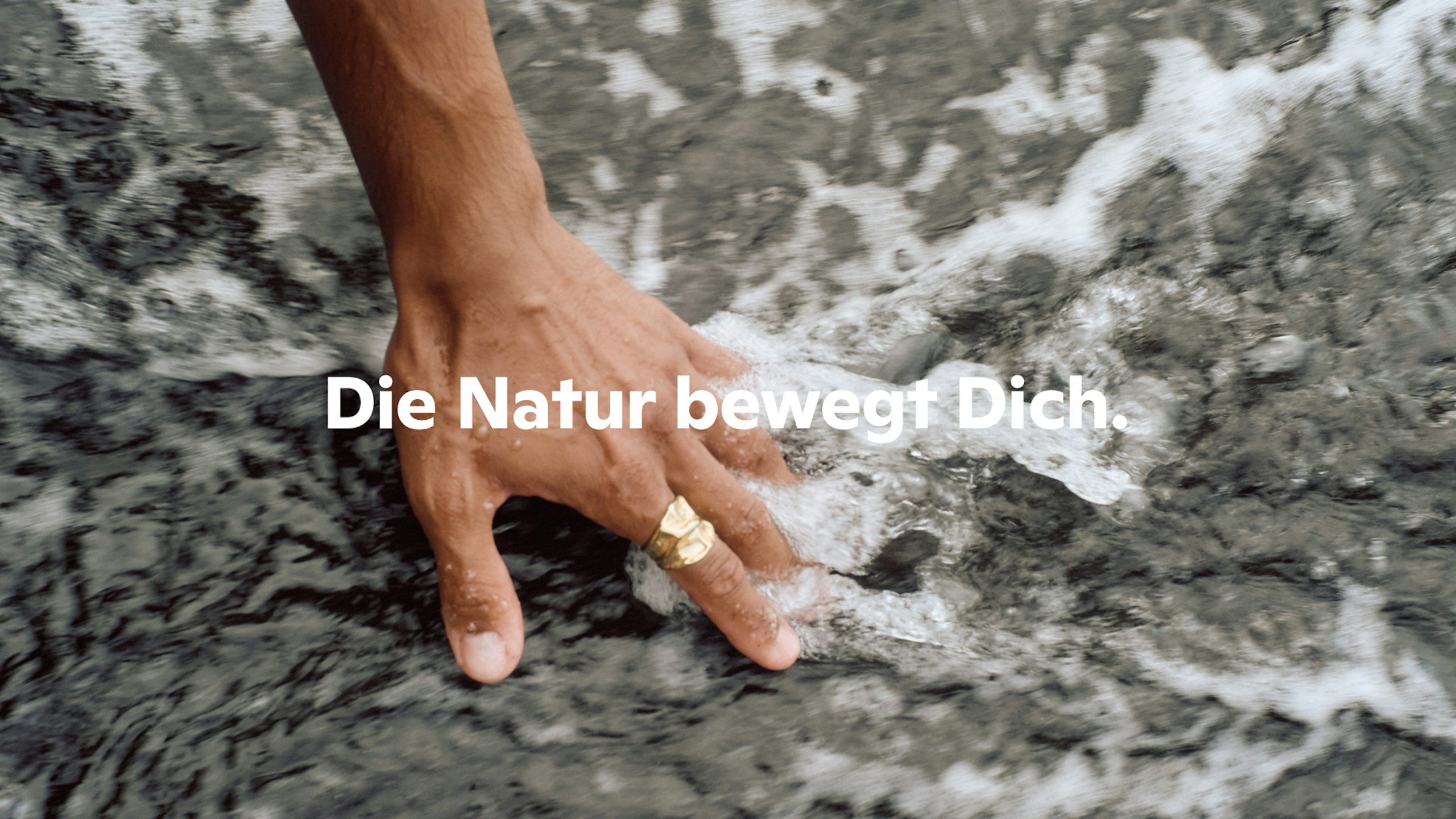 Hand berührt fließendes Wasser im Fluss - Spruch: "Die Natur bewegt Dich"