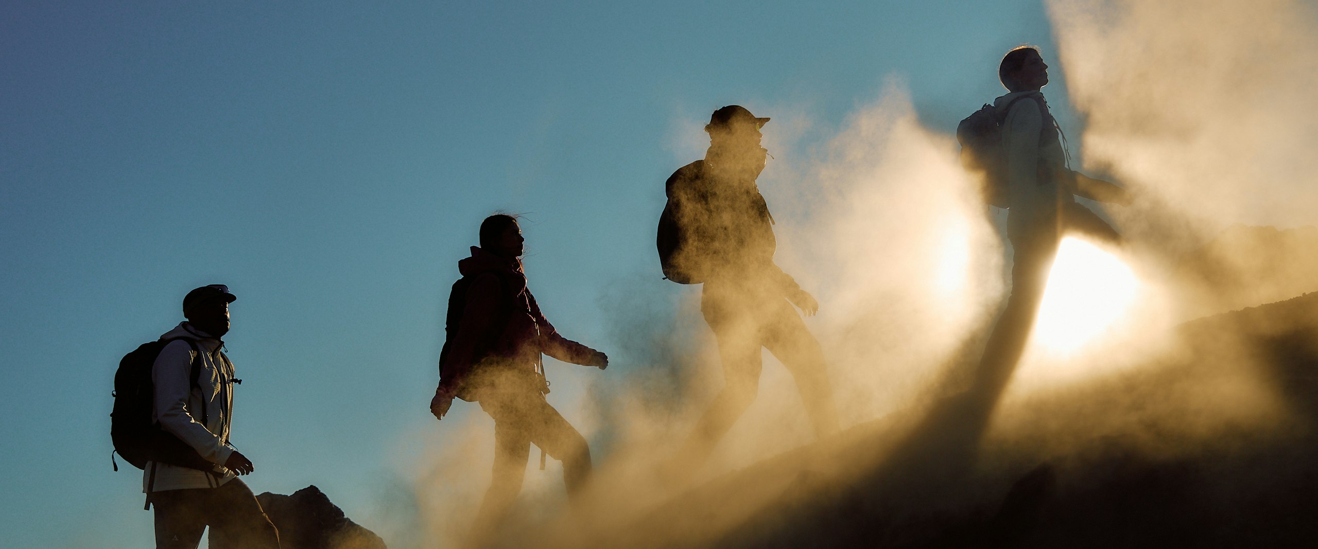 Personen laufen im Sonnenaufgab mit Nebel bergauf