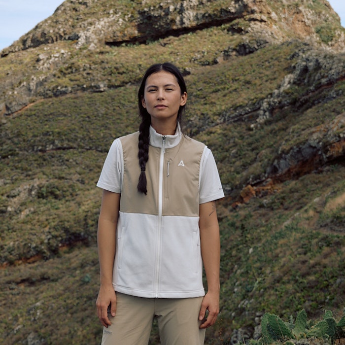 Frau steht mit beig/ weißer Wanderweste frontal zur Kamera 