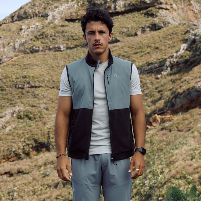 Mann steht in Wanderkleidung frontal zur Kamera und trägt dabei en Wanderoutfit mit Wanderweste