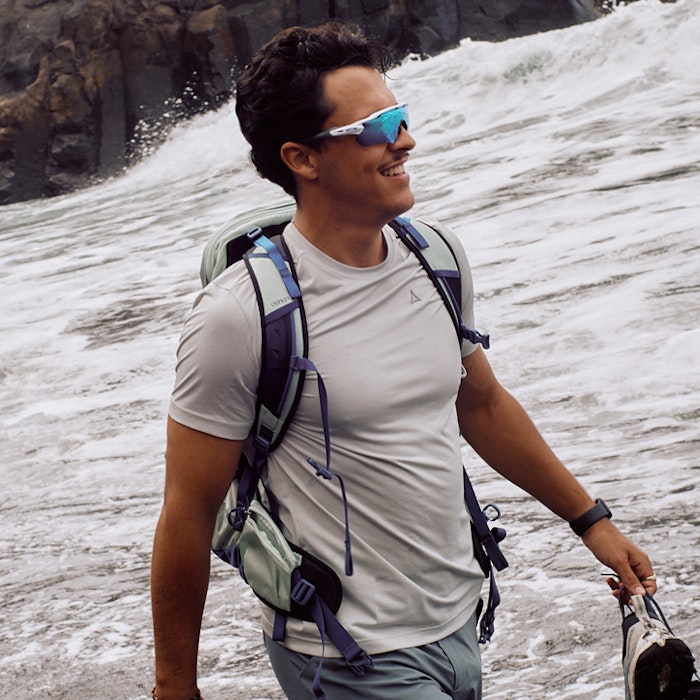 Wanderer am Strand mit Blick aufs Meer lächelnd