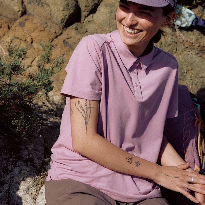 Wanderin in rosa Shirt in Sonne sitzend und lachend