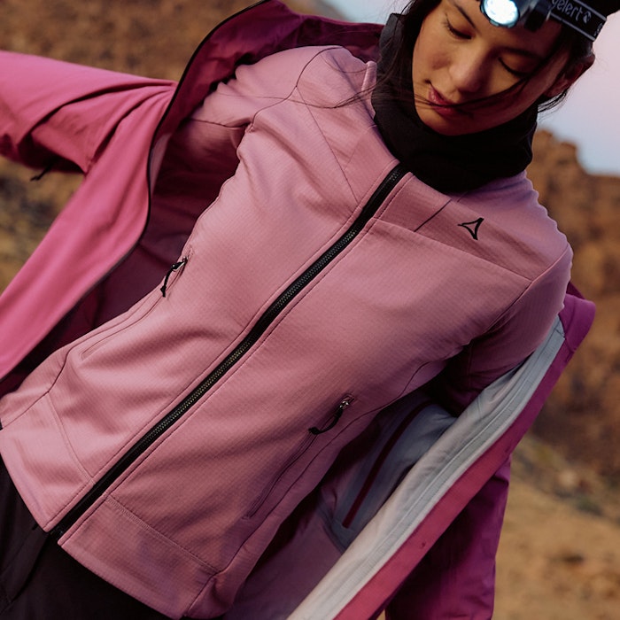 Frau in Wanderkleidung blickt nach unten in rose Fleece und rosa Jacke - zieht Jacke gerade an