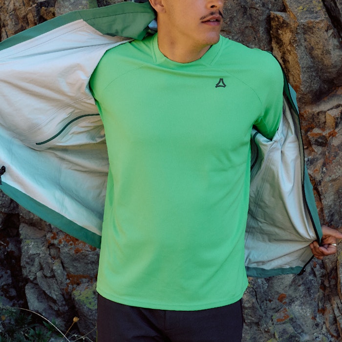 Mann in hell grünem Shirt zieht grüne Jacke aus 