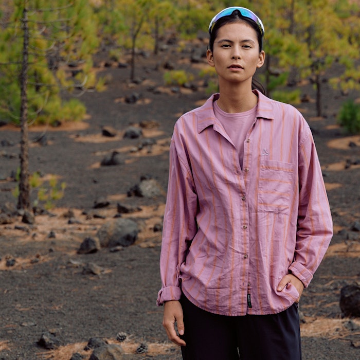 Frau steht mit lässigem Outfit frontal zur Kamera in rosa Hemd