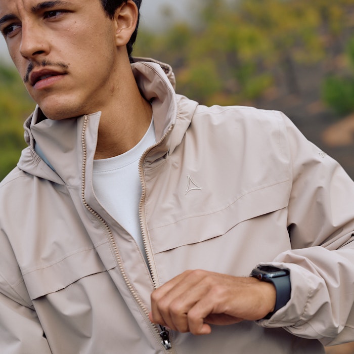 Mann in beiger Jacke öffnet Reißverschluss 