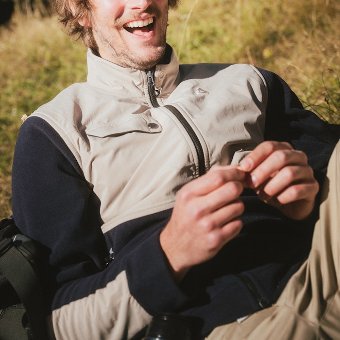 A man wearing a trekking fleece jacket is lying in the grass.