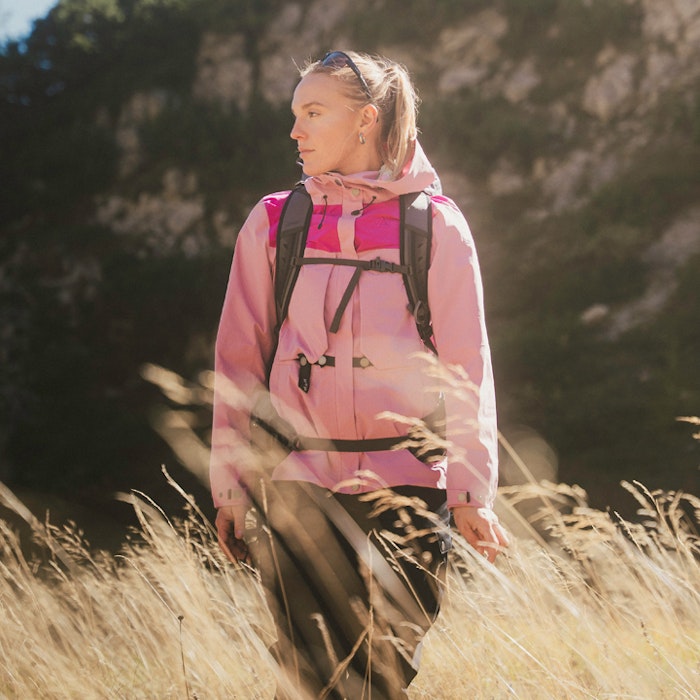 A lady in trekking gear runs through tall grass.