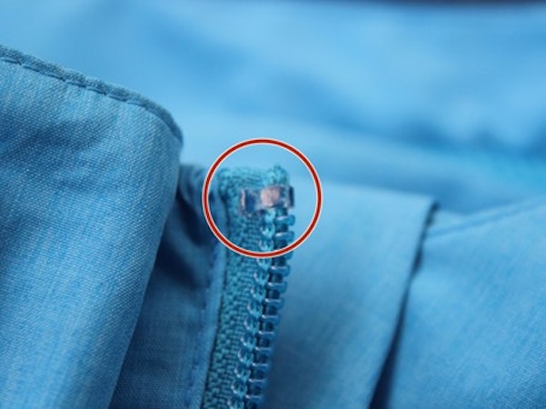 Endstück eines Reisverschlusses ist aufgebogen und rot eingekreist, Schöffel.