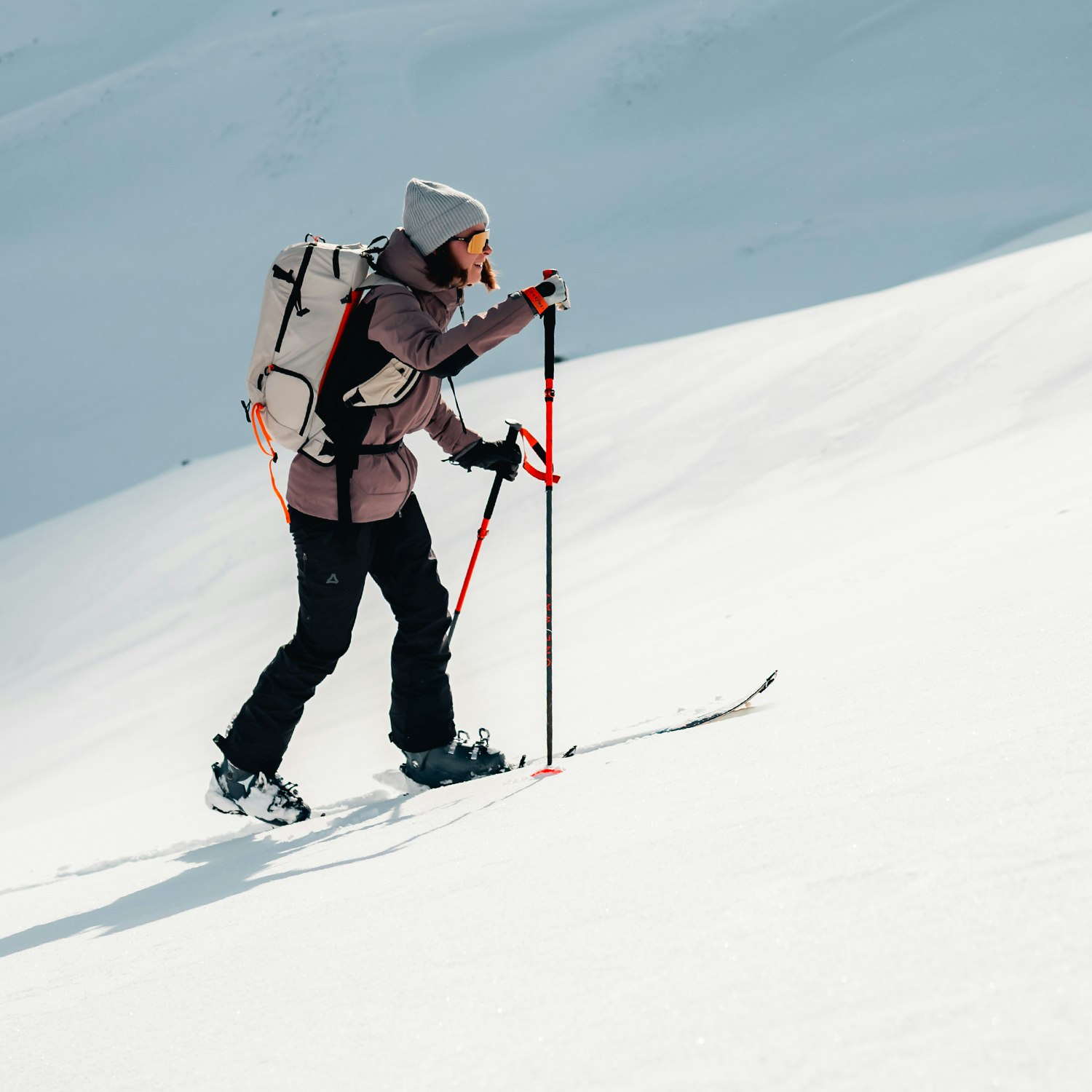 Eine Frau läuft mit Skiern einen schneebedeckten Berg hinauf, Schöffel.